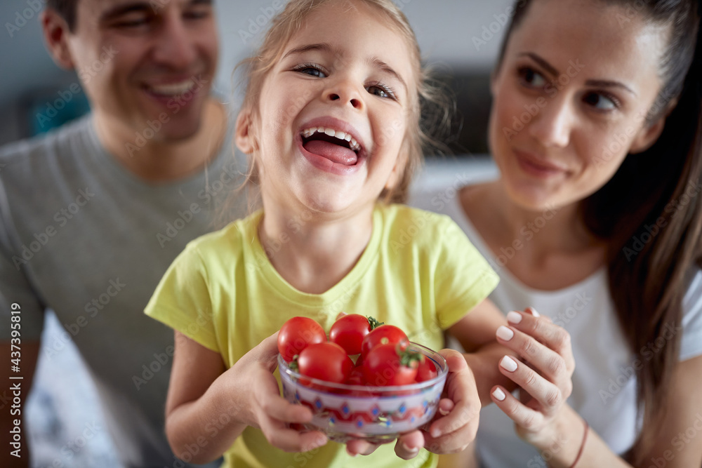 A cute little girl posing for a photo with her parents while they having a breakfast at home. Family, together, breakfast, home A cute little girl posing for a photo with her parents while they having a breakfast at home. Family, together, breakfast, home