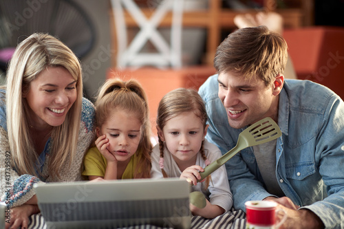 A young family watching a laptop content on the bed at home together. Family, together, love, home