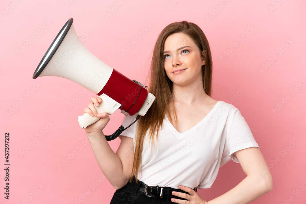 Teenager girl over isolated pink background holding a megaphone and thinking Teenager girl over isolated pink background holding a megaphone and thinking
