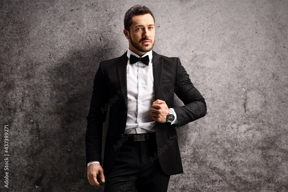 Young man in a black suit and bow tie leaning on a rusty gray wall Stock Photo | Adobe Stock Young Man In A Black Suit And Bow Tie Leaning On A Rusty Gray Wall Stock Photo | Adobe Stock