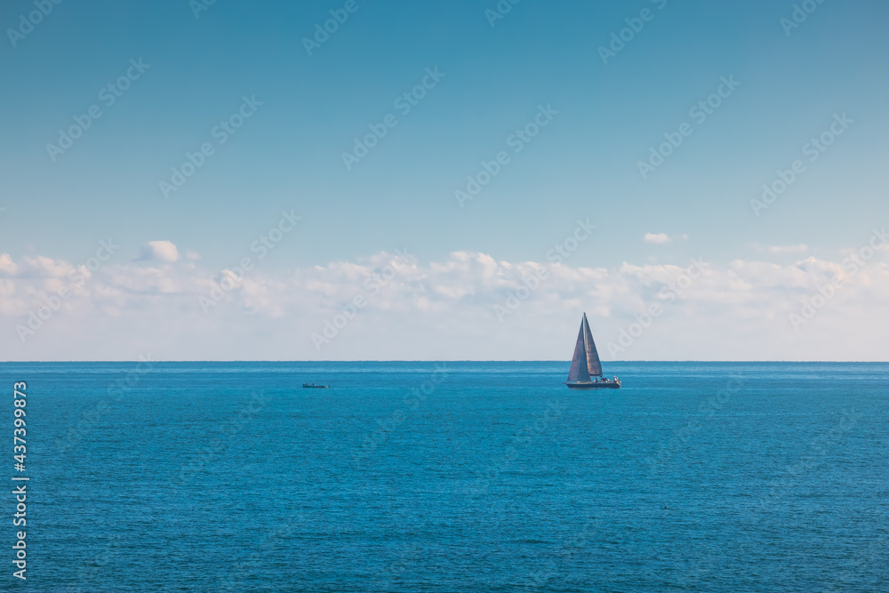 Obraz premium Sea and sailing wind boat. Sailboat over blue waves and sunny sky