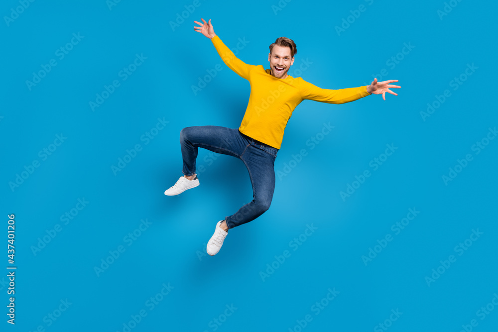 Full length body size of young guy jumping up cheerful laughing careless playful isolated bright blue color background
