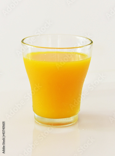 A glass of cold orange juice against white background