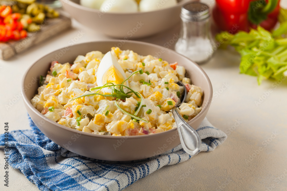 A light egg salad with celery, gherkin, pepper and mayonnaise. Served in a bowl on a light background. Front view. A light egg salad with celery, gherkin, pepper and mayonnaise. Served in a bowl on a light background. Front view.