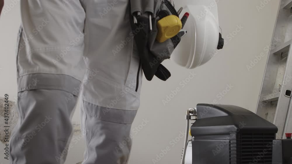 construction man worker wearing a tool bag belt, helmet with headphones ...