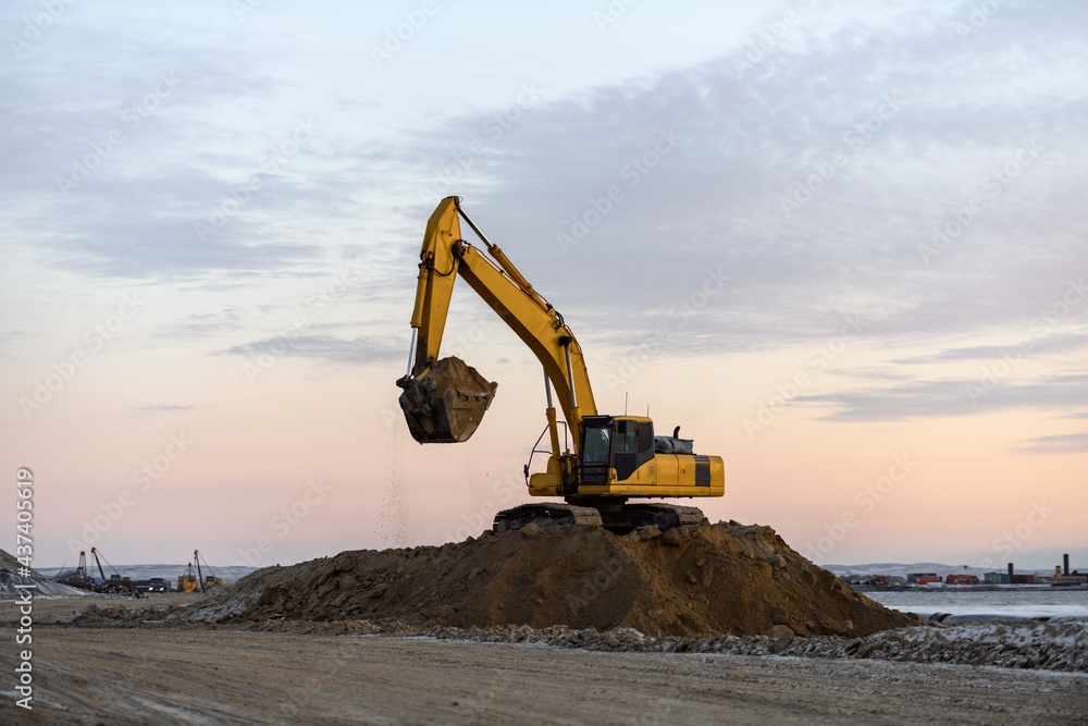 Yellow excavator working on construction site. The road construction. Yellow excavator working on construction site. The road construction.