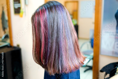 Coloring several strands of dark hair pink and purple. Hairstyle in the salon