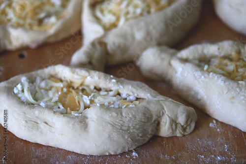 Raw khachapuri on a wooden board. Cooking homemade khachapuri. © Oksana