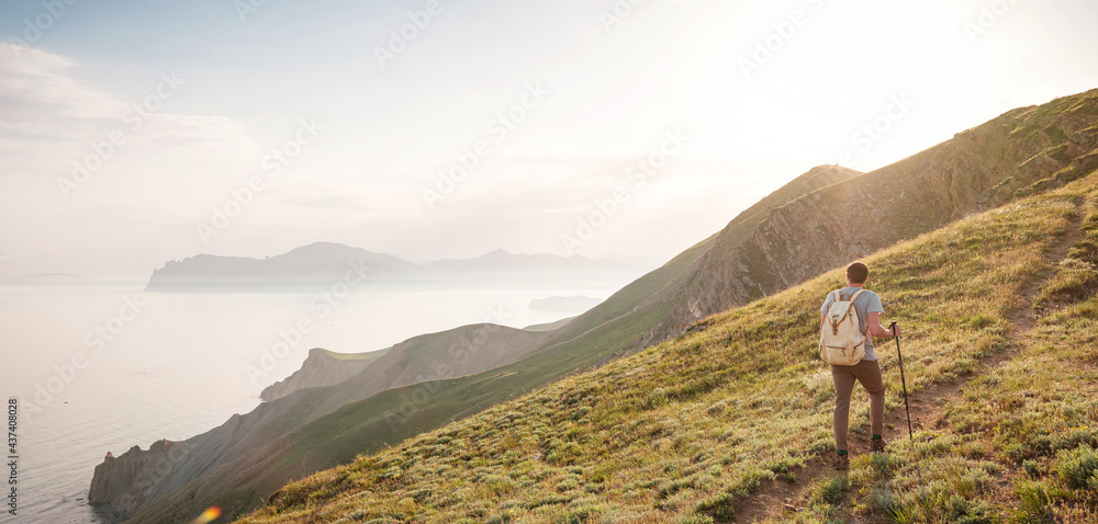 Young man travels alone on the backdrop of the mountains