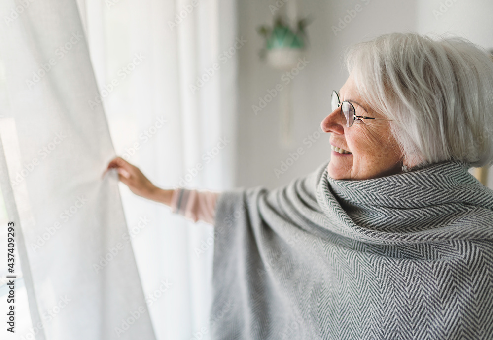 Middle aged female in front of curtains close to a window Middle aged female in front of curtains close to a window
