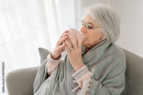 portrait of elderly woman sit on the sofa at home with coffee or tee