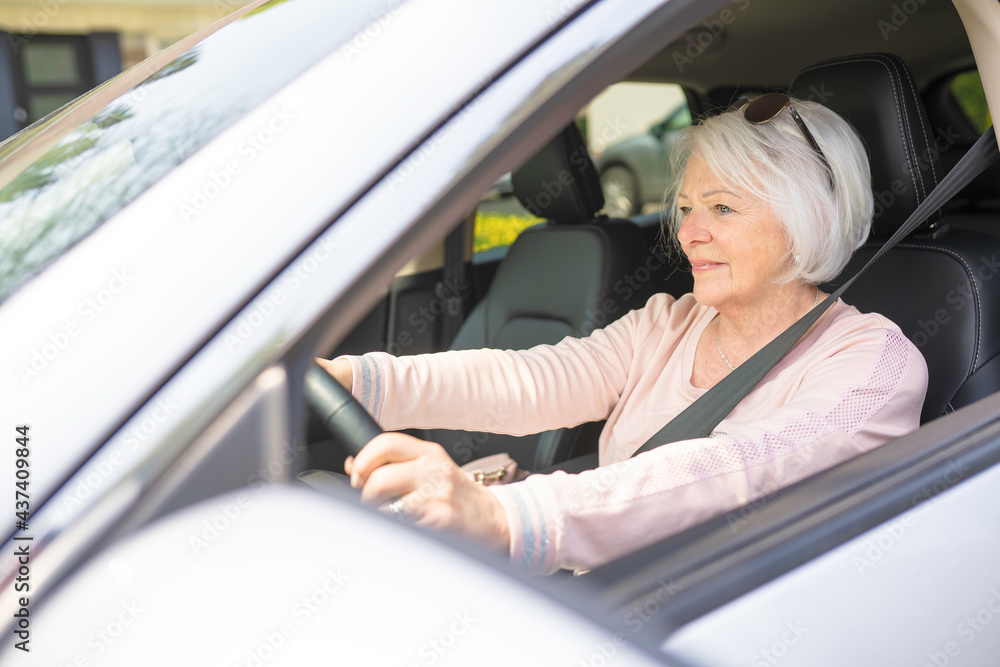Happy and smiling senior woman in white car