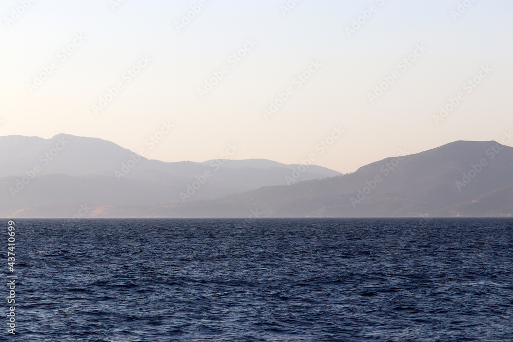 View from the blue sea to mountains and seaside in mist. Beach vacation and travel concept