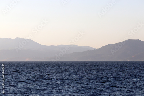 View from the blue sea to mountains and seaside in mist. Beach vacation and travel concept