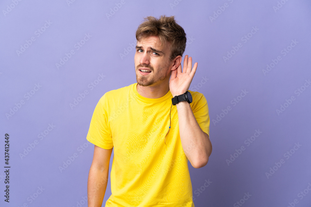 Young handsome blonde man isolated on purple background listening to something by putting hand on the ear Young handsome blonde man isolated on purple background listening to something by putting hand on the ear