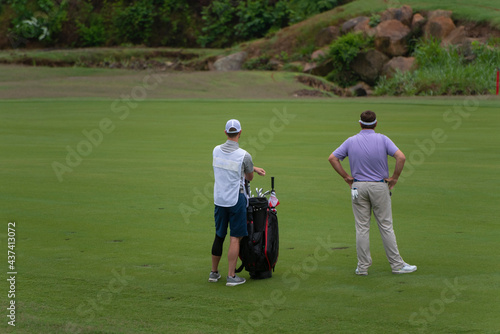 A golfer and his caddy look down the fairway during a tournament.  photo