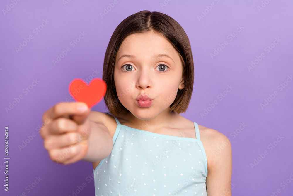 Photo of cheerful young small girl give little red paper heart shape you isolated on violet purple color background Photo of cheerful young small girl give little red paper heart shape you isolated on violet purple color background