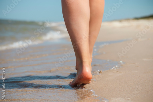 Beautiful legs of a young girl walk along the beach