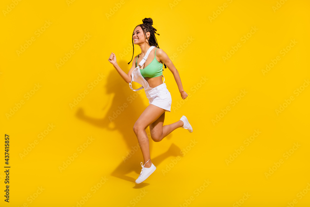 Full length photo of brunette afro american young woman jump up run empty space isolated on yellow color background Full length photo of brunette afro american young woman jump up run empty space isolated on yellow color background