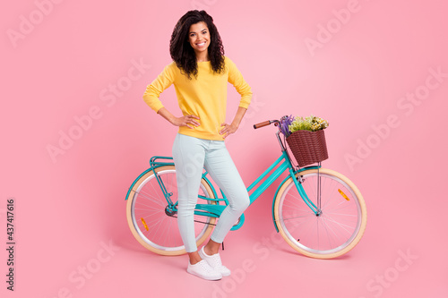 Fototapeta Naklejka Na Ścianę i Meble -  Full length body size view of pretty content cheerful girl with bike hands on hips isolated over pastel pink color background