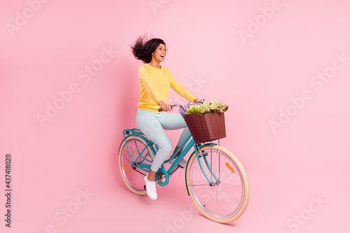 Portrait of pretty cheerful girl riding bike having fun fast speed motion isolated over pastel pink color background © deagreez