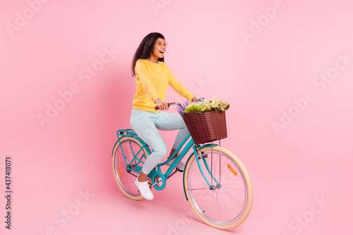 Portrait of attractive amazed cheerful girl riding bike having fun isolated over pastel pink color background © deagreez