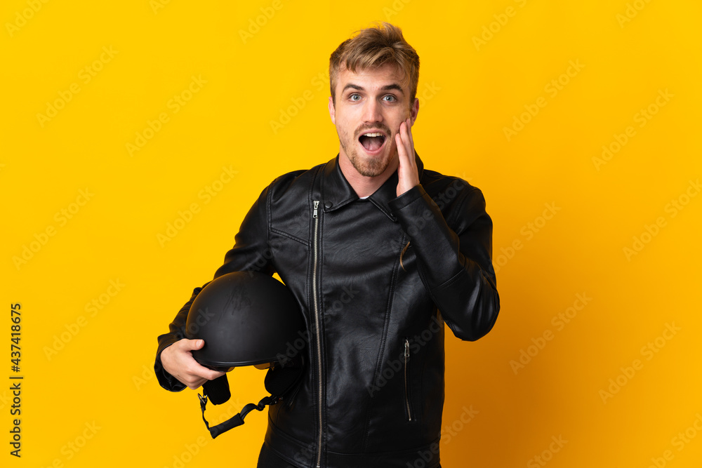 Man with a motorcycle helmet isolated on yellow background with surprise and shocked facial expression Man with a motorcycle helmet isolated on yellow background with surprise and shocked facial expression