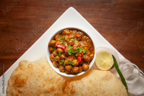 Chickpeas masala (Spicy chola or chhole curry) and Bhatura or Puri garnished with fresh green coriander and ingredients. A Classic Indian typical Panjabi street food. photo