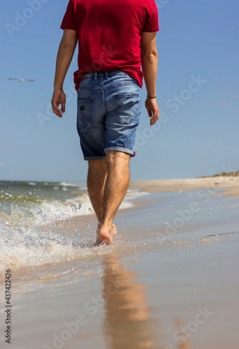 Beautiful young male legs walk along the beach. Warm summer weather © Margo