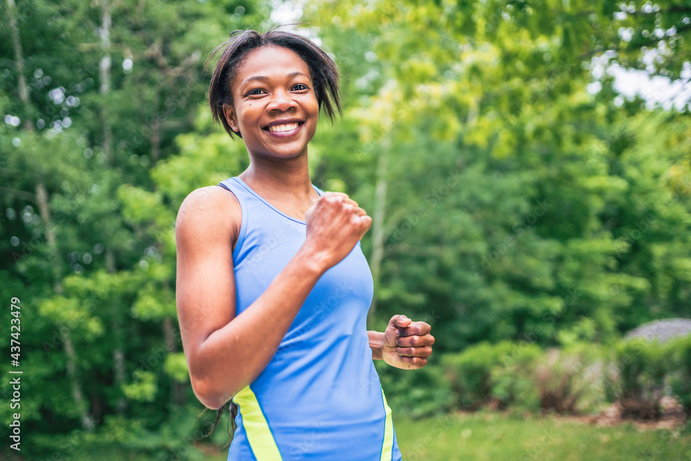 Woman runner in action outside in tree background Woman runner in action outside in tree background