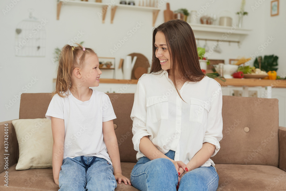 The trusting relationship of mom and daughter. Conversation of a woman with a little girl at home on the couch in the kitchen. Best friends happy motherhood weekend together with kid concept The trusting relationship of mom and daughter. Conversation of a woman with a little girl at home on the couch in the kitchen. Best friends happy motherhood weekend together with kid concept