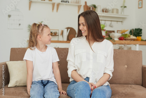 The trusting relationship of mom and daughter. Conversation of a woman with a little girl at home on the couch in the kitchen. Best friends happy motherhood weekend together with kid concept