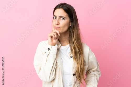 Young caucasian woman isolated on pink background and thinking