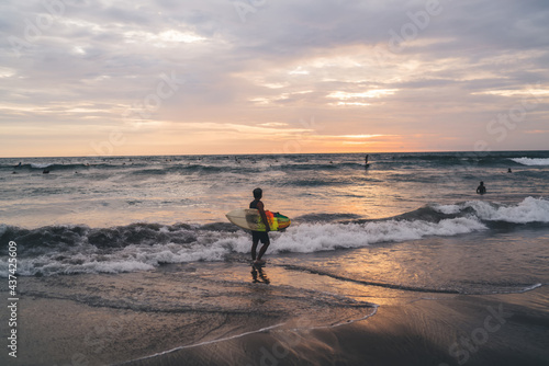 Unrecognizable man holding surf board and looking at ocean