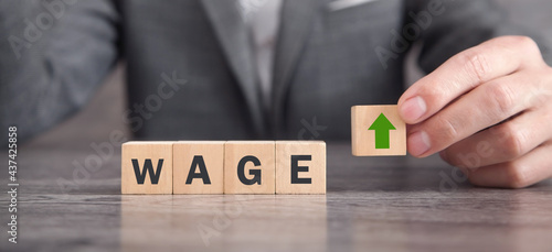 Man showing wooden cube with a up arrow and Wage word.