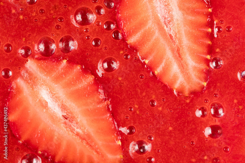 Food background. Strawberry slices in a strawberry smoothie. Red background, close-up, top view.
