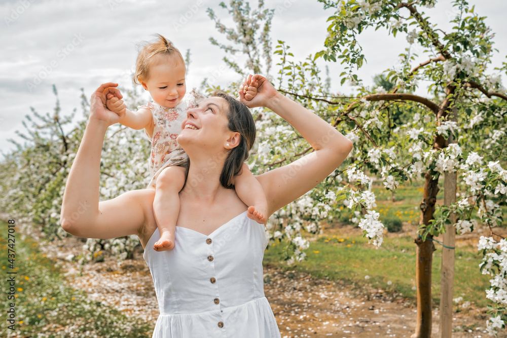 Obraz premium portrait of mother and baby girl outdoors in apple tree flower