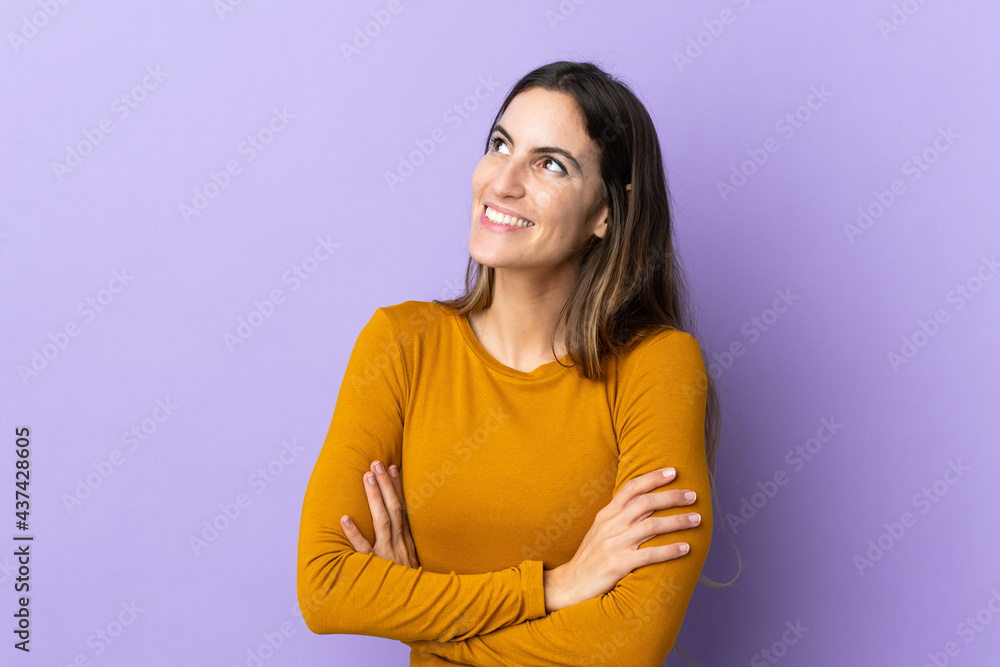 Obraz premium Young caucasian woman over isolated background looking up while smiling