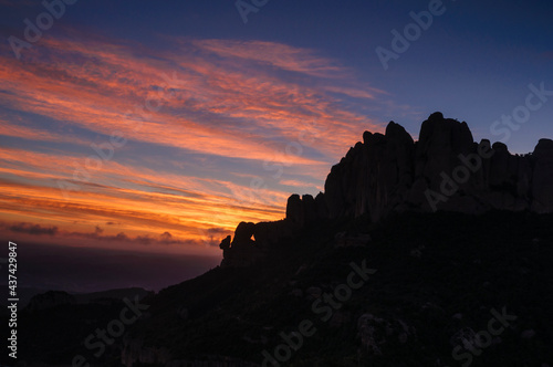 Montserrat west face and Roca Foradada seen from Sant Pau Vell de la Guàrdia at sunrise with red sky (Barcelona province, Catalonia, Spain)