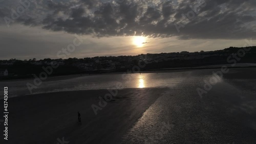 Evening cloudy golden sunset colours across Benllech beach silhouette coastline Anglesey aerial view slow left pull away photo