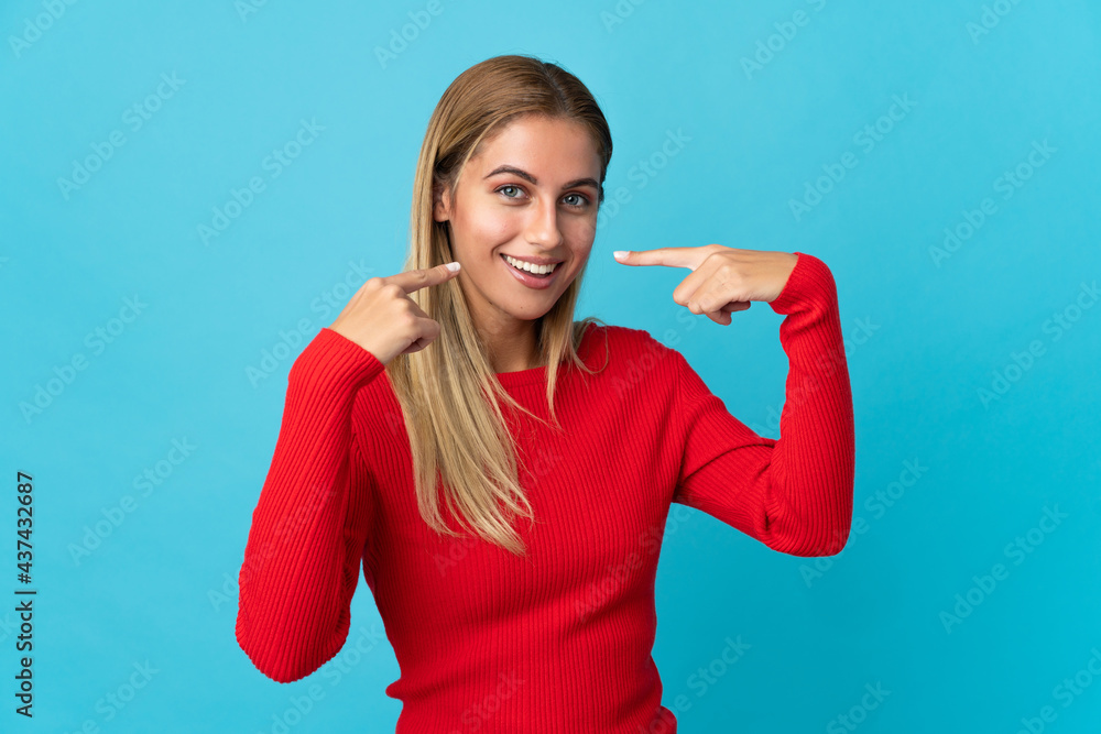 Young blonde woman isolated on blue background giving a thumbs up gesture Young blonde woman isolated on blue background giving a thumbs up gesture