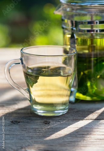 A cup of mint tea on a wooden table in the summer garden	
