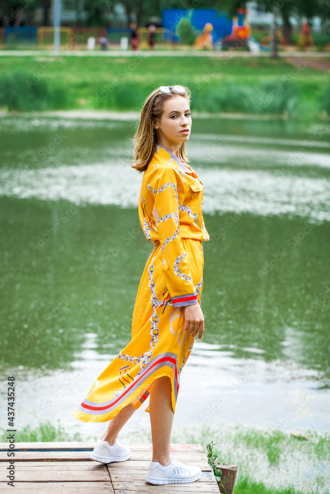 Portrait of a young beautiful woman in dress posing by the lake Portrait of a young beautiful woman in dress posing by the lake