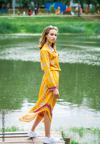 Portrait of a young beautiful woman in dress posing by the lake