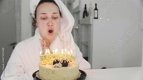 Young cheerful girl celebrates a birthday and blows out candles on a holiday cake