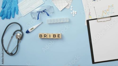 Doctor puts wooden cubes with the collected word bribe with hands. Concept of corruption in medicine. photo