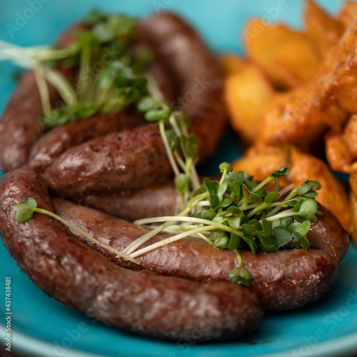 Fried sausages with microgreens. Junk Food concept. Close up shot. Soft focus. Square format.
