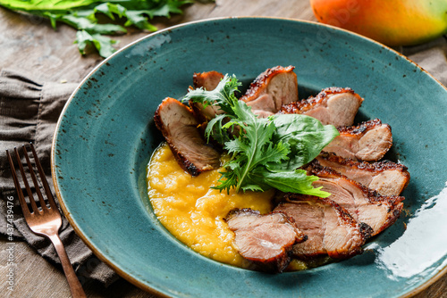Grilled turkey fillet with mango puree in plate on wooden background. Summer food, meat dish, selective focus, close up