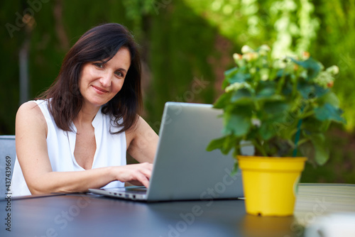 Woman typing on her laptop while looking at camera