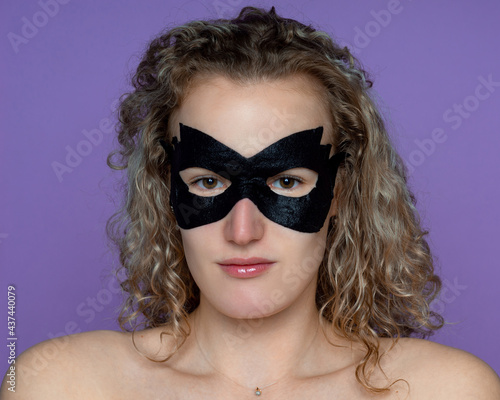Girl in a black cosmetic mask, for skincare, eliminates bags under her eyes
